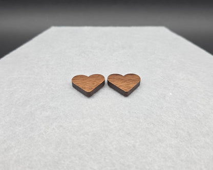 Walnut wood heart stud earrings at an angle showing thickness, handmade by Rainbow Charlie