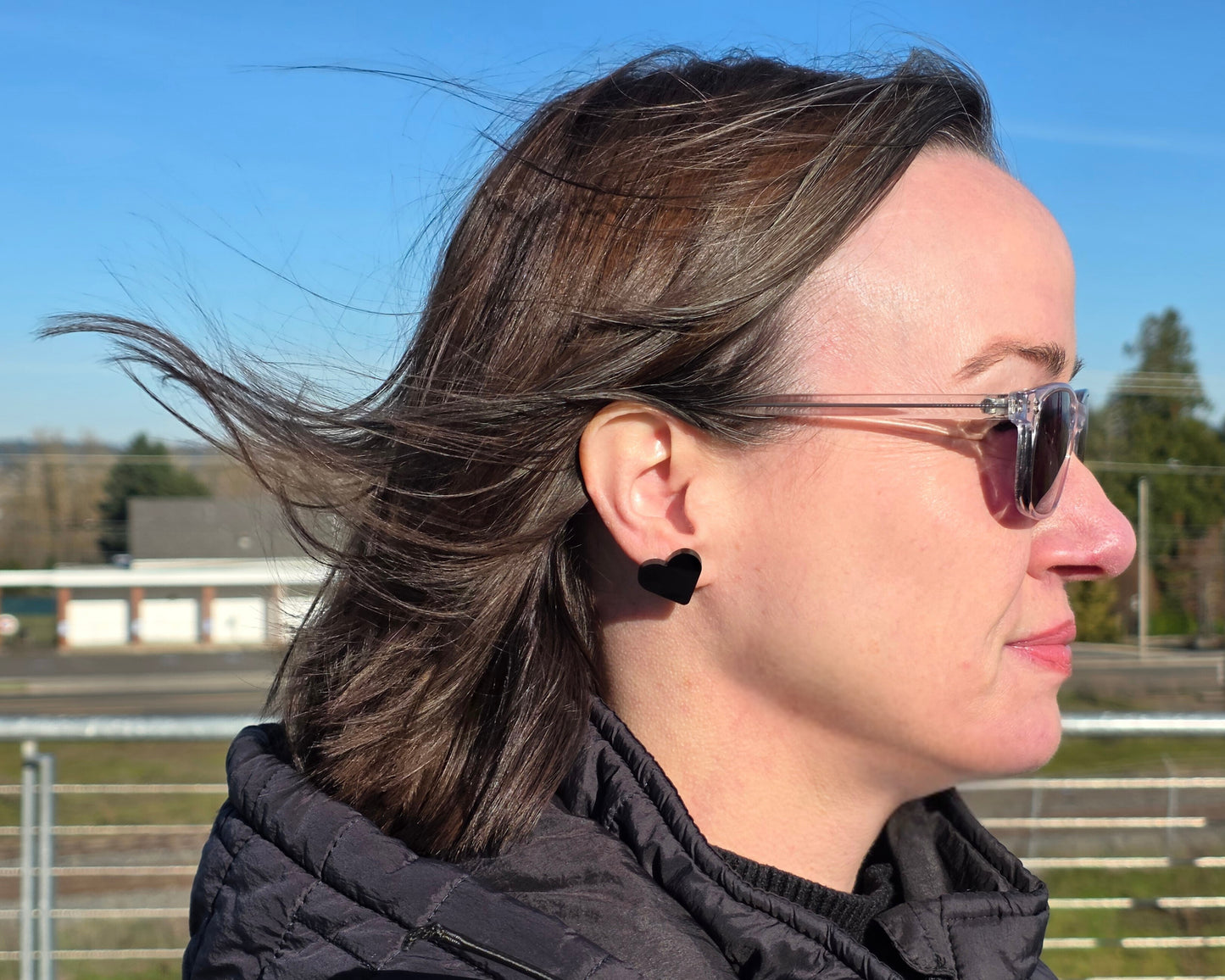 Black acrylic heart stud earring worn on ear outdoors, hypoallergenic titanium post earrings by Rainbow Charlie