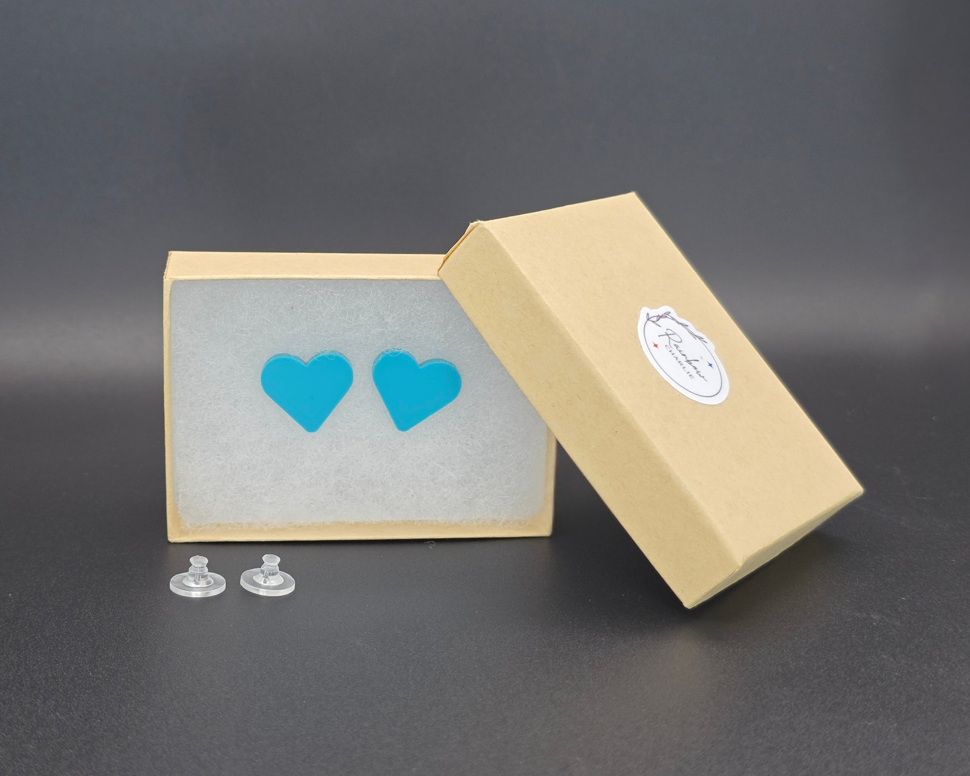 Teal acrylic heart stud earrings in Rainbow Charlie kraft gift box with silicone backs, handmade earring packaging