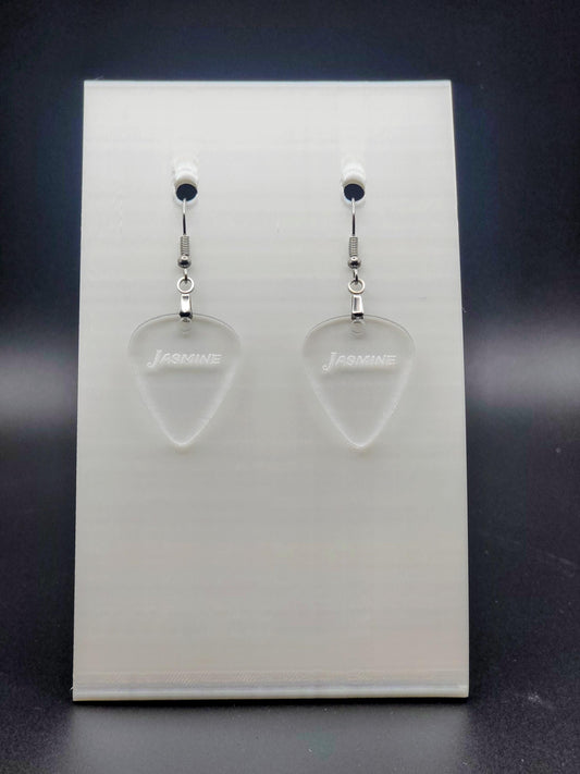 Clear acrylic guitar pick earring with "Jasmine" engraved, shown on a white jewelry card. Fun, personalized jewelry for music lovers.