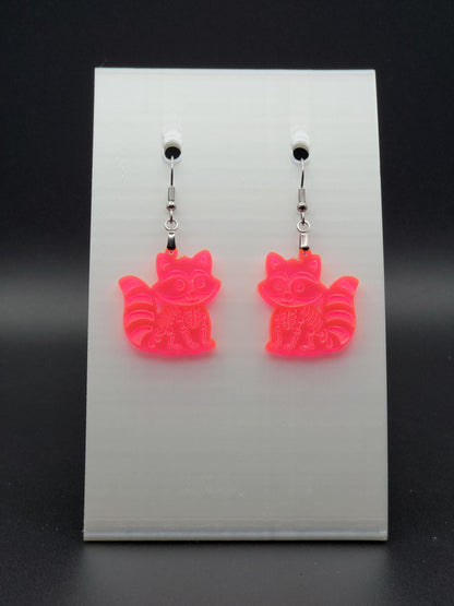 Fluorescent acrylic skeleton raccoon dangle earring with engraved bone details and stainless steel hook, displayed on a white jewelry card. Laser-cut, handmade spooky jewelry.