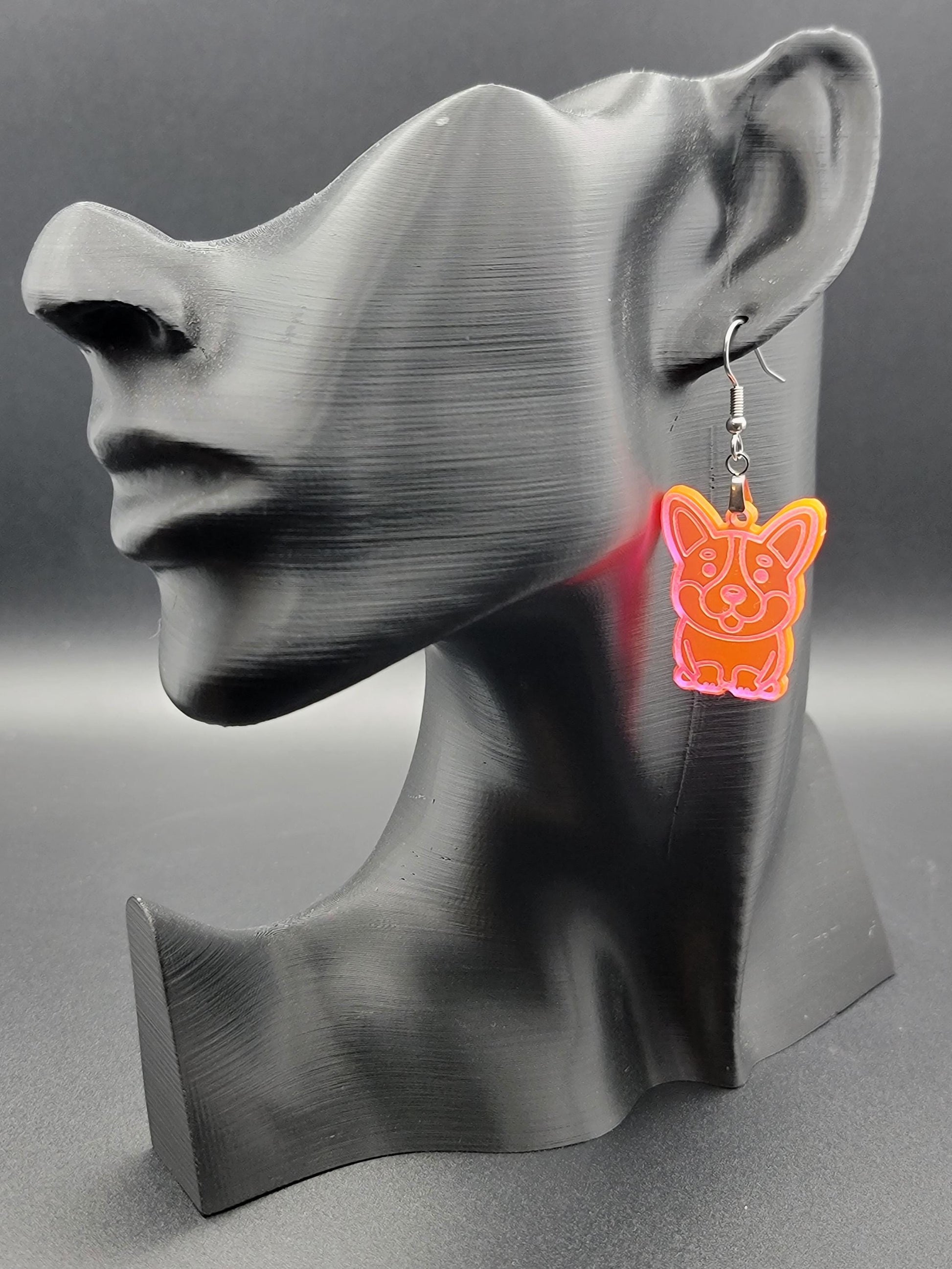 Fluorescent laser-cut acrylic corgi earring displayed on a black 3D printed mannequin. Lightweight dangle with stainless steel hook.