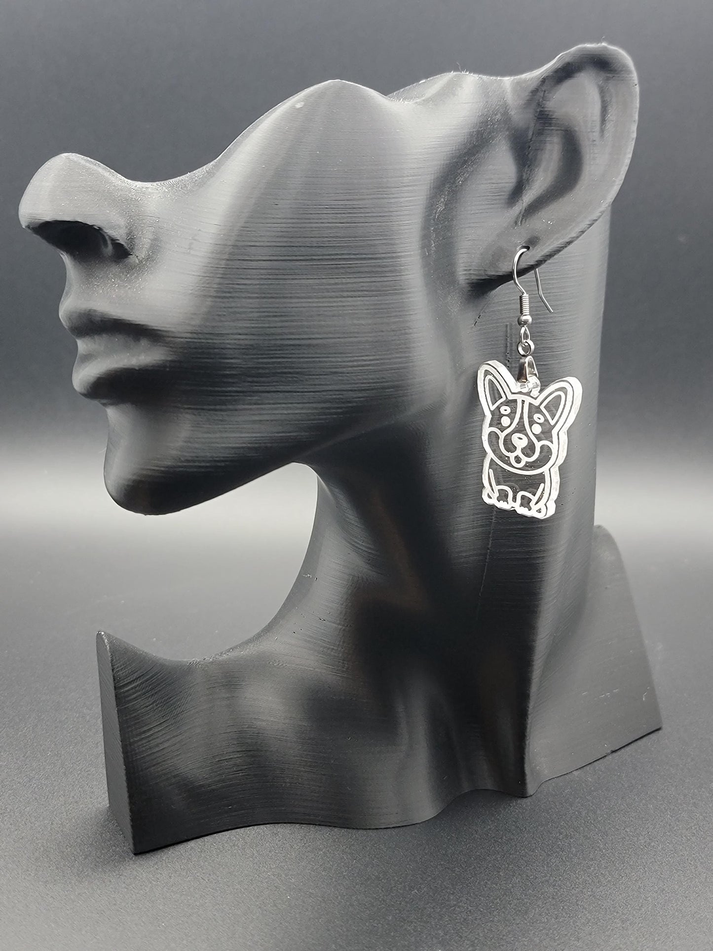 Clear laser-cut acrylic corgi earring displayed on a black 3D printed mannequin. Lightweight dangle with stainless steel hook.