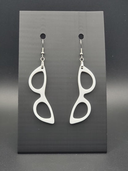 White acrylic cat-eye glasses dangle earrings on a matte black jewelry card. Handmade, laser-cut retro jewelry.