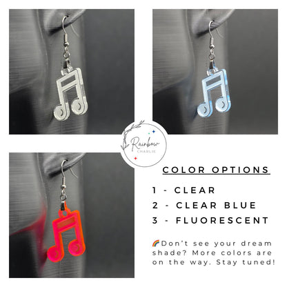 Three acrylic music note earrings shown on a mannequin ear in different colors: clear, clear blue, and fluorescent. Text on the image lists color options and mentions more coming soon. Rainbow Charlie logo in the corner.