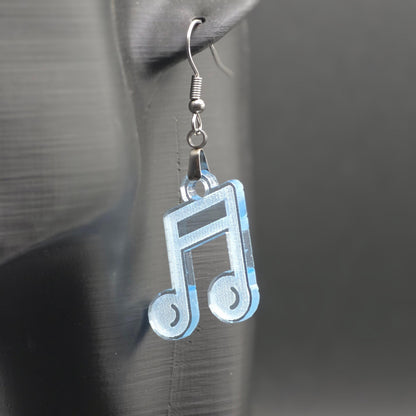 Single earring made of clear blue acrylic shaped like a beamed music note, hanging from a mannequin ear. Matte black background emphasizes color and shine.