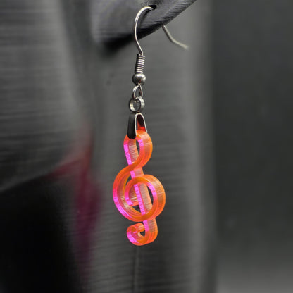 Fluorescent acrylic treble clef earring on matte black mannequin ear, showcasing laser-cut detail and stainless steel hardware.