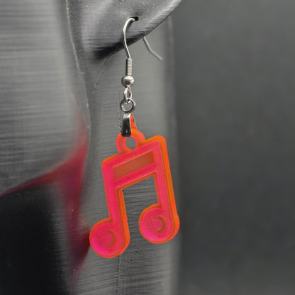 Single earring made of fluorescent acrylic shaped like a beamed music note, hanging from a mannequin ear. Matte black background emphasizes color and shine.