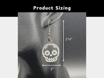 Clear acrylic skull earring displayed on a matte black mannequin head with measurements shown. Earring measures approximately 2¼ inches in length and 1 inch in width. White arrows and text provide visual scale for shoppers.