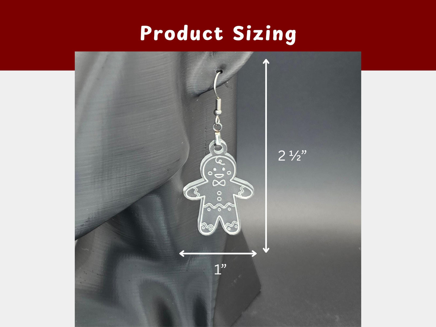 Close-up of frosted acrylic gingerbread man earring on display stand with white measurement lines. Dimensions show 2½ inches long by 1 inch wide. Text heading reads “Product Sizing.”