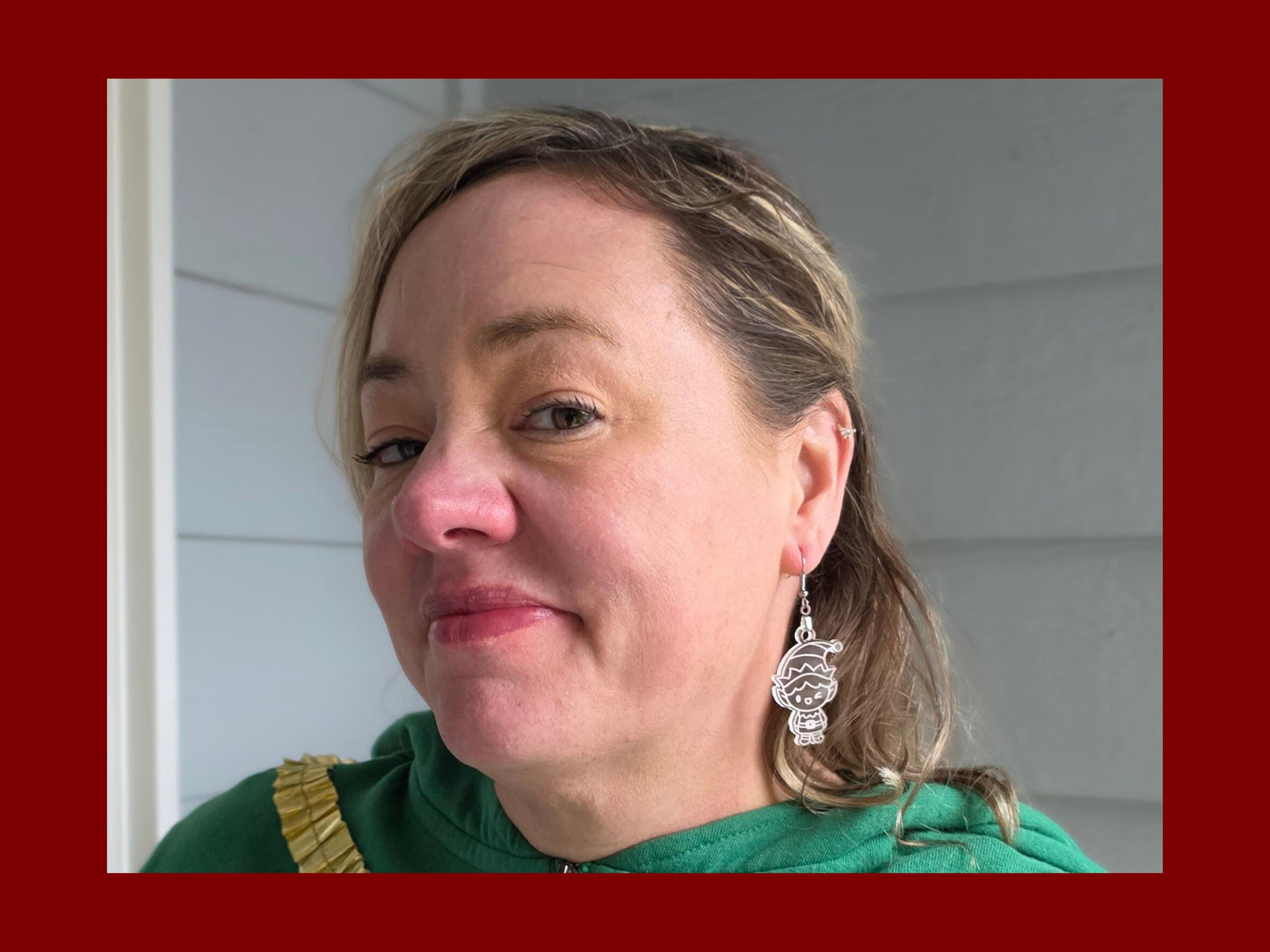Close-up of a woman wearing the frosted acrylic elf dangle earrings, showing their size and how they hang from the ear. The translucent white design is clearly visible, with nickel-free hooks, against a neutral outdoor background.