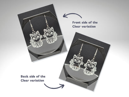 Front and back view of clear frosted acrylic cat earrings shown on a jewelry display stand. The front engraving is bold and visible, while the back engraving shows a lighter outline. Text labels and arrows identify each side.