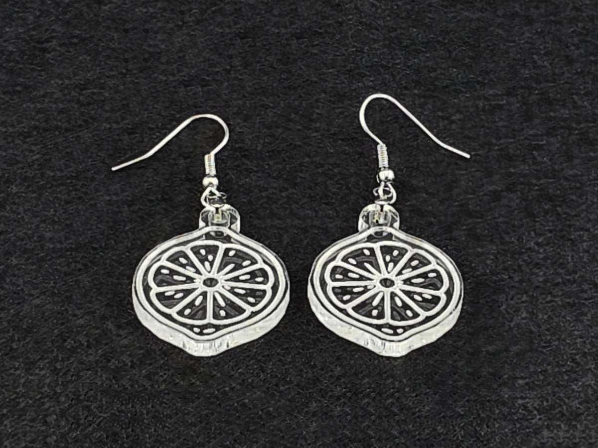 Clear acrylic lemon slice earrings shown at an angle, highlighting the engraved citrus detail and cut edge.