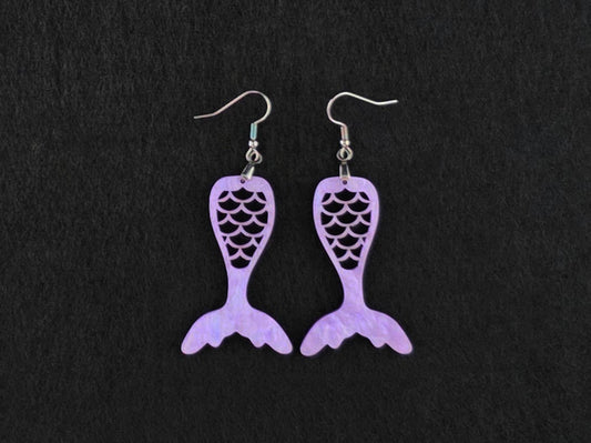 Pair of lavender acrylic mermaid tail earrings with stainless steel French hook earwires, laid flat on a charcoal background.