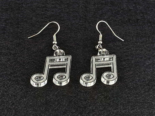 Pair of clear acrylic beam note earrings shown at an angle on a charcoal background, highlighting the cut linework with no color tint.